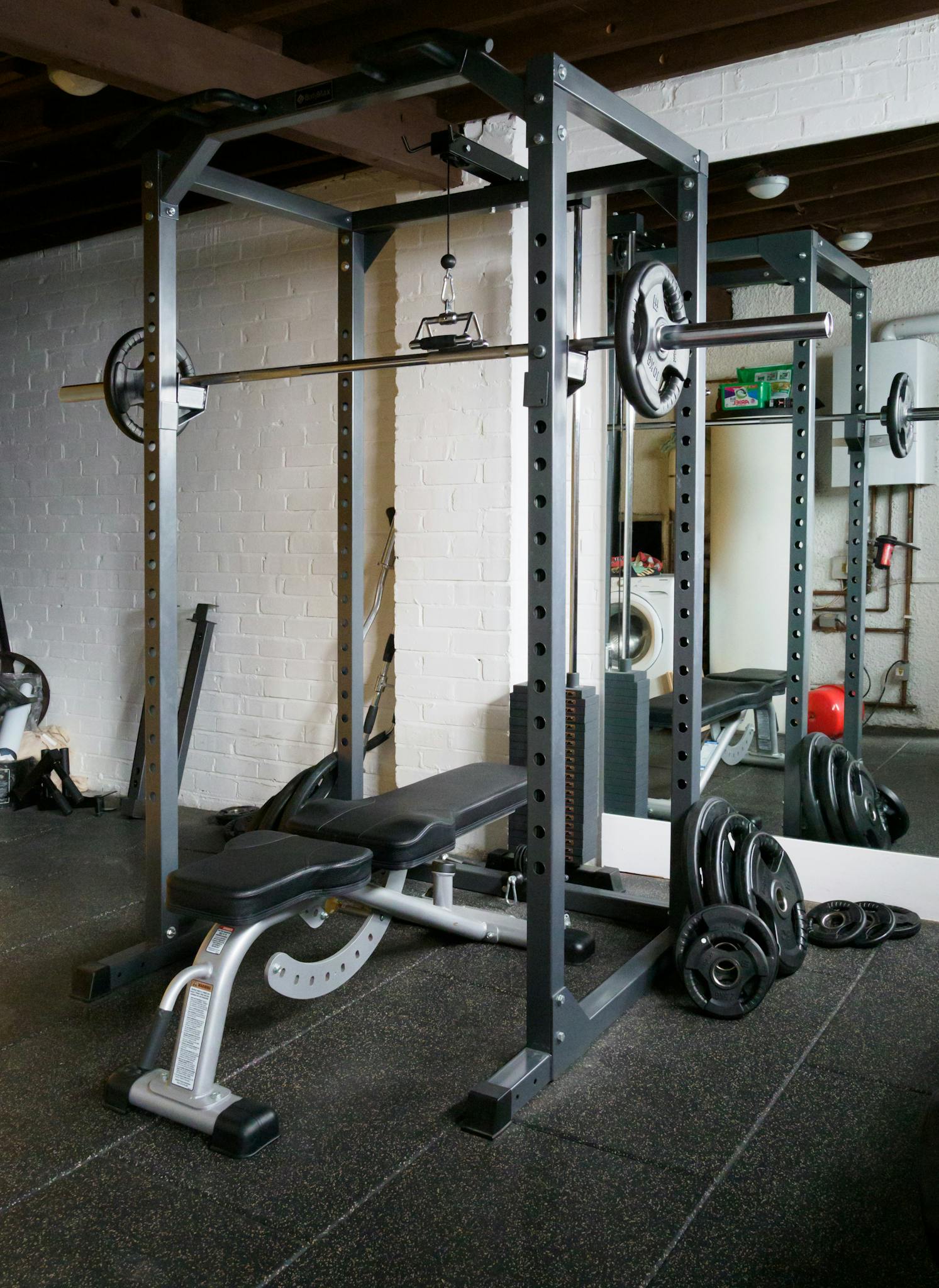 A home gym setup featuring a weight bench, barbell, and mirror for fitness training.