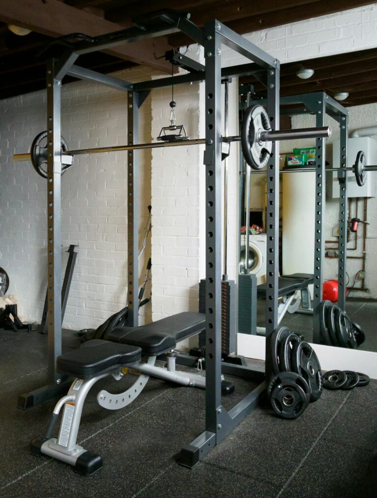 A well-equipped gym featuring a barbell setup with weights and a mirror.