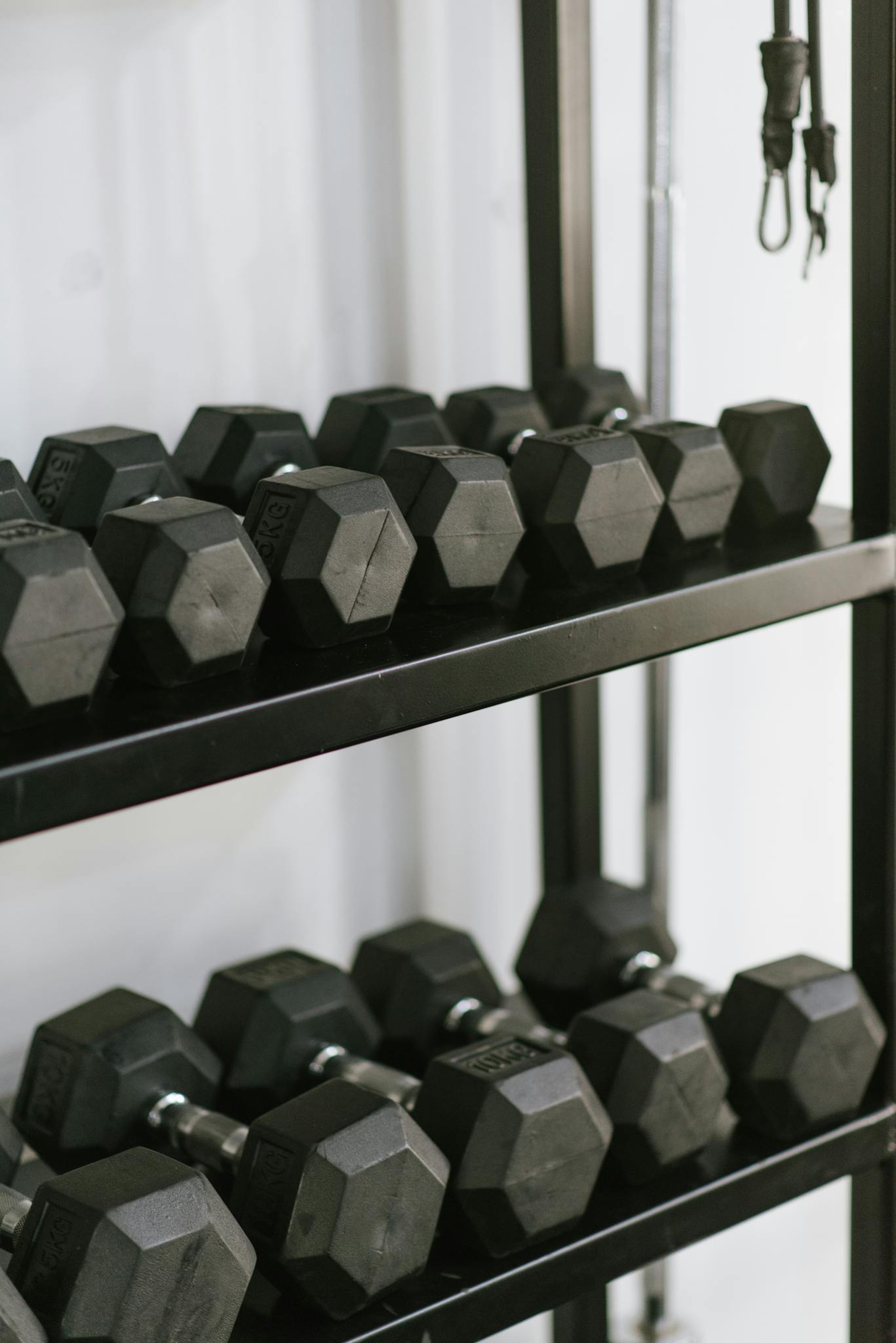 Organized hexagonal dumbbells stacked on a sturdy rack in a modern gym setting.